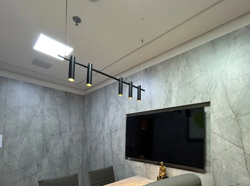 Sala com paredes em mármore cinza, mesa e luminária pendente